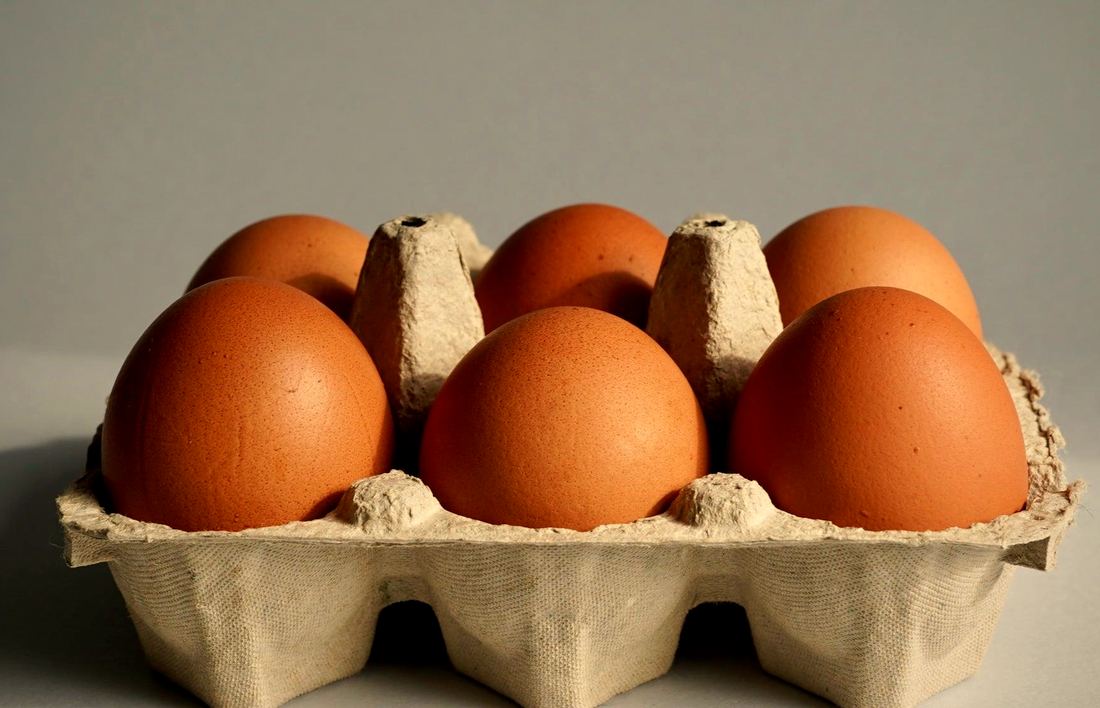 Seis ovos vermelhos numa bandeja de papelão
